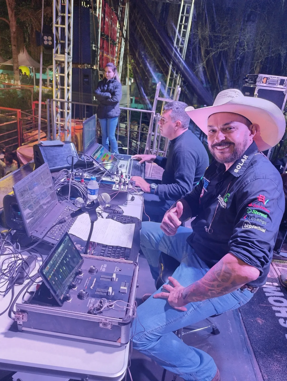 Profissional de evento diante de computadores e equipamentos com DJRodeio em operação